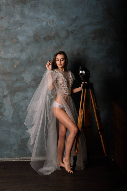 Morning of the bride. Portrait of a beautiful young woman in a white underwear and a peignoir. - Photo, Image