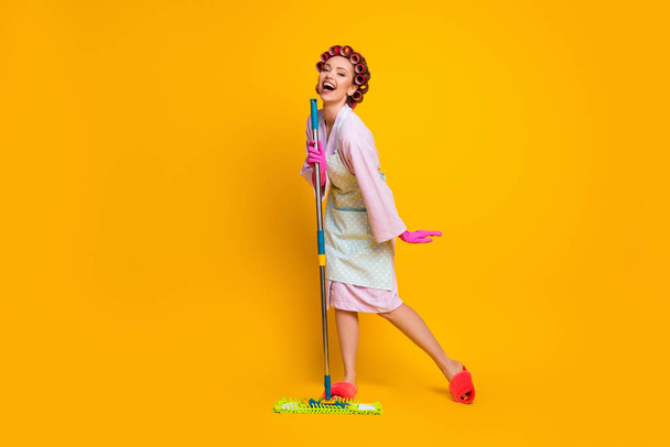 Full length body size view of attractive cheery maid singing pop hit using mop like mic isolated bright yellow color background - Valokuva, kuva