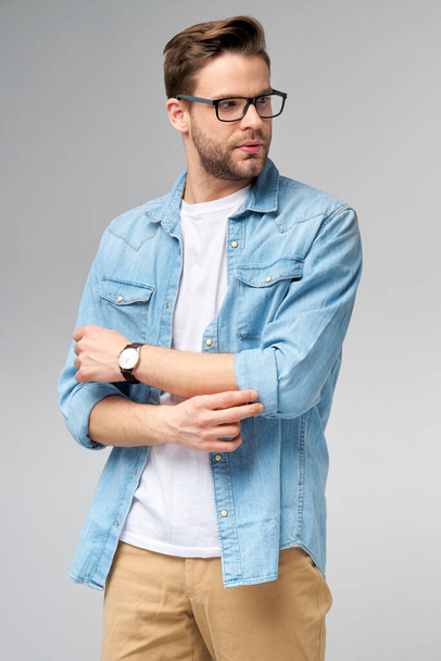 Portrait of young handsome caucasian man in jeans shirt over light background - 写真・画像
