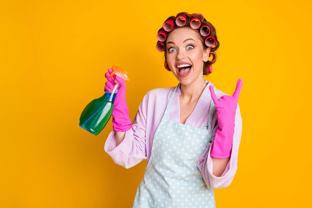 Crazy girl use chemical spray bottle show horned symbol wear bath robe gloves isolated yellow color background - Valokuva, kuva