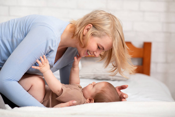 Madre cariñosa acariciando a su bebé en la cama - Foto, imagen