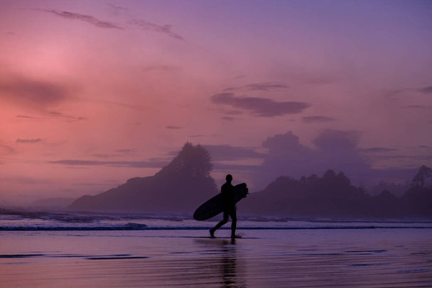 Vancouver Island Tofino, zonsondergang aan het strand met surfers in de oceaan, prachtige kleurrijke zonsondergang met roze en paarse kleuren aan de hemel bij Vancouver Island met mensen surfen - Foto, afbeelding