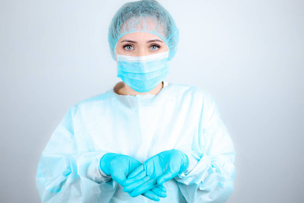 Медсестра в медицинском халате, маске и защитных перчатках протянула руки перед ней. - Фото, изображение