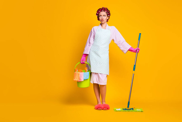 Oh no many chores . Upset girl hold bucket mop look copyspace wear bath robe isolated bright color background - Фото, изображение