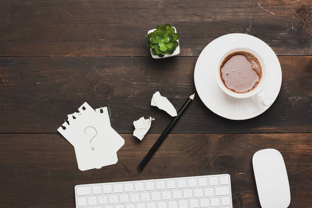 bílá bezdrátová klávesnice a šálek kávy na dřevěném hnědém stole, výhled shora, pracoviště - Fotografie, Obrázek