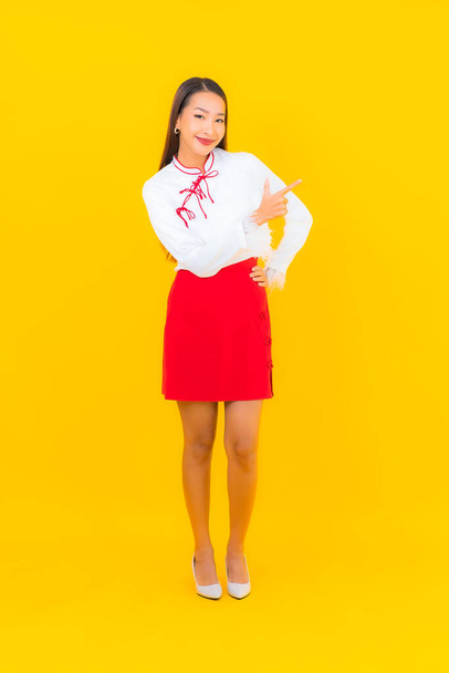 Portrét krásná mladá asijská žena úsměv v akci na žlutém pozadí - Fotografie, Obrázek