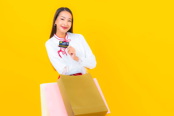 Portrait beautiful young asian woman with shopping bag and credit card on yellow background - Photo, Image