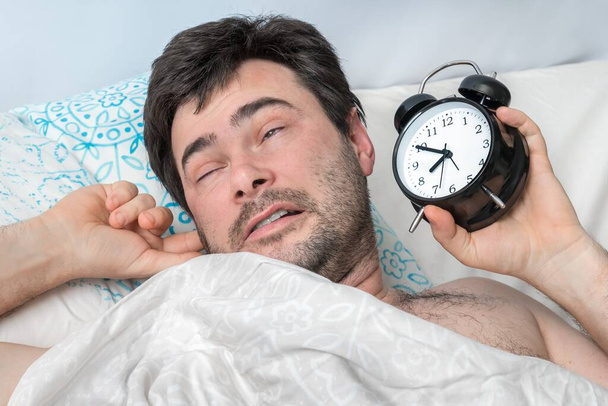 Çalar saati olan yorgun bir adam erken kalkmak istemez. - Fotoğraf, Görsel
