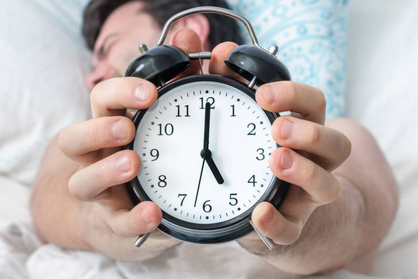 Tired man with alarm clock does not want waking up at early - Photo, image