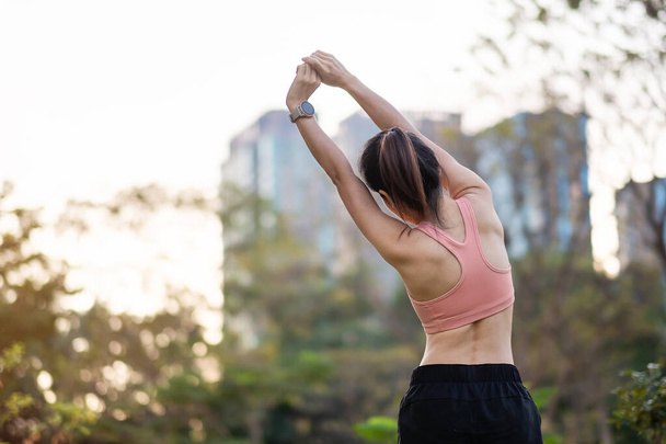 Junge erwachsene Frauen in pinkfarbener Sportbekleidung dehnen Muskeln im Park im Freien, Sportlerinnen wärmen sich auf, um morgens zu laufen und zu joggen. Wellness, Fitness, Bewegung und Work Life Balance Konzepte - Foto, Bild