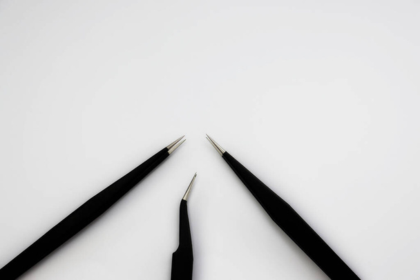 Τρεις μαύρες αντιστατικές λαβίδες απομονωμένες σε λευκό φόντο - Φωτογραφία, εικόνα