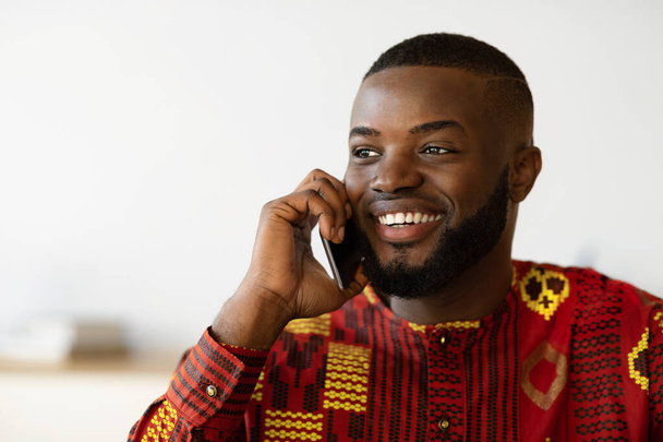 Mobil çağrı. Etnik tişörtlü gülümseyen Afrikalı Amerikalı Cep telefonuyla konuşuyor - Fotoğraf, Görsel