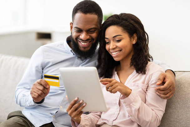 Black couple using tablet and debit credit card at home - Foto, Imagem
