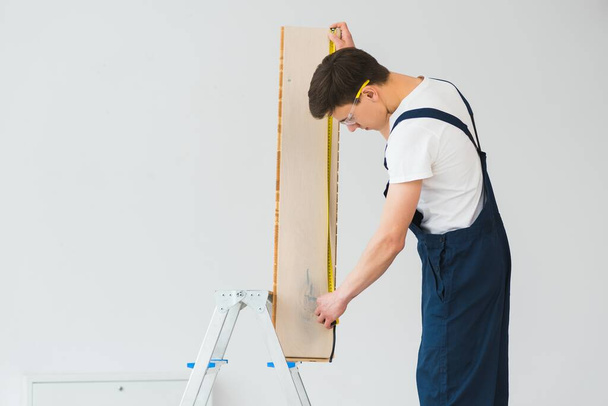 Worker with materials for installing laminate flooring - Fotó, kép