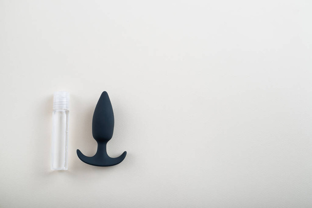 Top view of black butt plug and bottle of lubricant on white background. Safe anal sex concept. Copy space - Foto, immagini