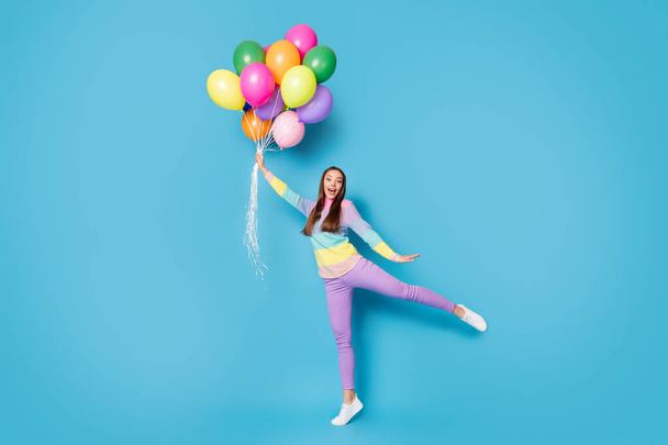 Full body photo of astonished girl hold catch air fly balloons scream wear pants isolated over blue color background - Fotografie, Obrázek