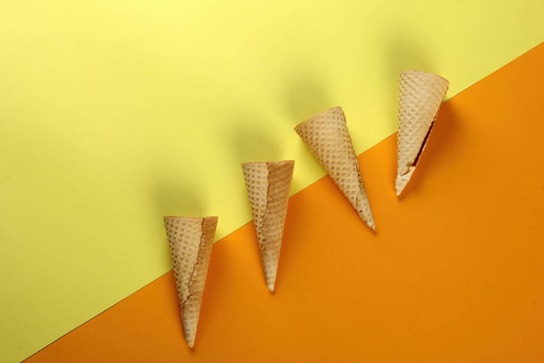 Emty Ice cream cones pattern on yellow background. Top view.Set of empty wafer ice cream cones - Foto, Imagen