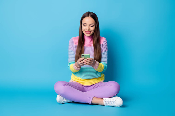 Portrait of lovely focused cheerful girl sitting lotus position crossed legs using app 5g isolated bright blue color background - Фото, изображение