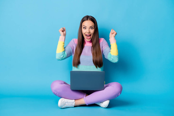 Portrait of pretty glad cheerful girl sitting lotus position crossed legs using laptop having fun isolated over bright blue color background - Foto, Imagem