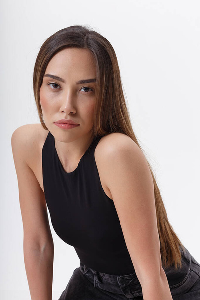 портрет молодой привлекательной азиатки с длинными темными волосами в черной одежде - Фото, изображение