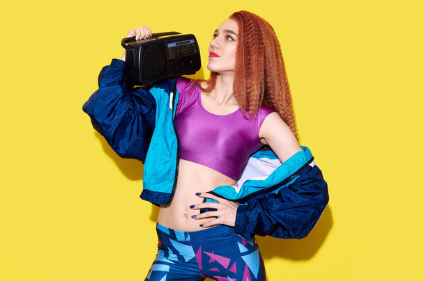 Hipster DJ κυρία φορώντας φωτεινά ρούχα κρατήσει ρετρό ταινία boom box. Party time μουσική λάτρης έννοια - Φωτογραφία, εικόνα