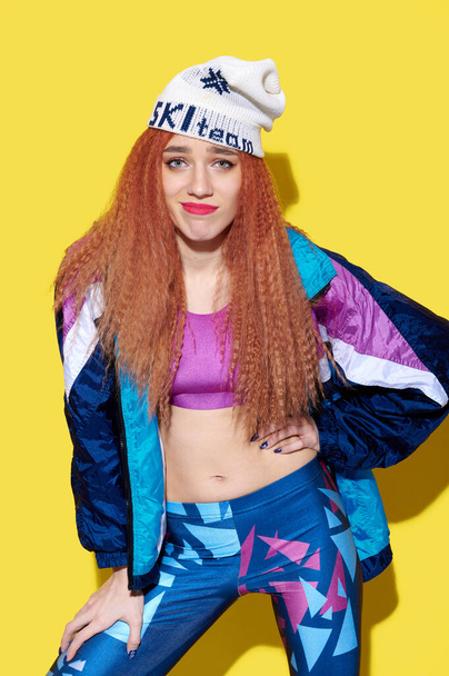 Funny young caucasian girl wearing retro clothes and hat posing and have fun over bright yellow background - 写真・画像