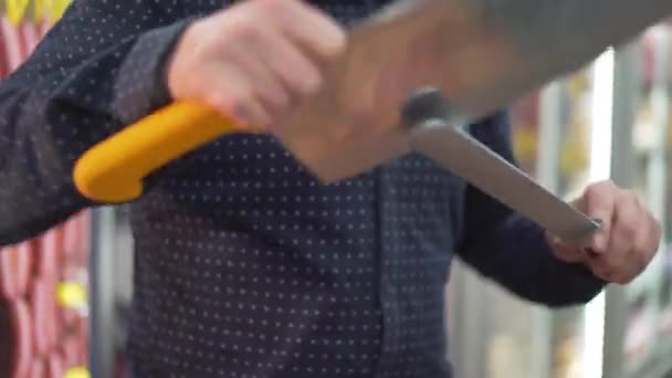 Ένας άνθρωπος ακονίζει ένα μαχαίρι κρέατος - Πλάνα, βίντεο