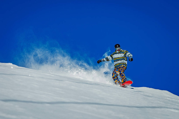 Snowboarder frenando y haciendo una nube de nieve en la montaña. Deportista montando en snowboard en Gudauri, Georgia - Foto, Imagen