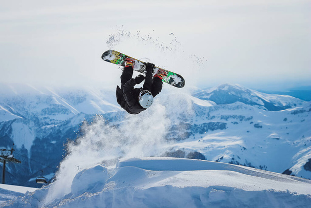 Сноубордист стрибає і робить трюк у горах
 - Фото, зображення