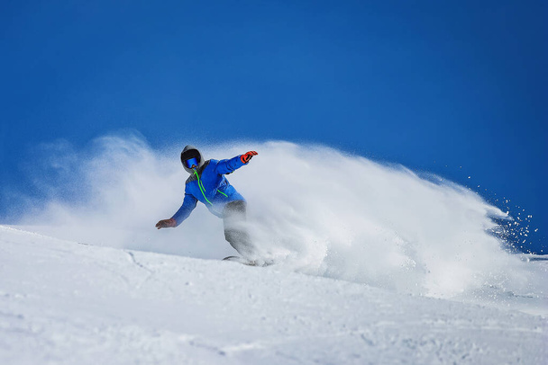 Сніговик гальмує і створює хмару снігу в горах. Спортсмен їде на сноуборді в Гудаурі, Джорджія. - Фото, зображення