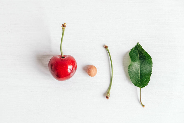 Fresh ripe cherry with green leaf on the white wooden background. Top view. Copy, empty space for text. - Φωτογραφία, εικόνα