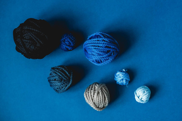Balls of threads of dark blue, light blue, gray colors on a blue background. Top view. Copy, empty space for text. - Photo, Image