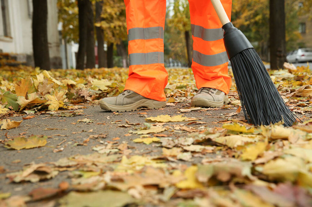 Street cleaner sweeping fallen leaves outdoors on autumn day - Foto, immagini