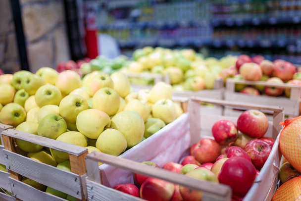 Soft focused shot of fruit department in grocery store, supermarket, mall, hypermarket or shopping center. Boxes of multicolored apples. Healthy eating, avitaminosis, diet, organic, vegan food concept.  - Foto, Bild