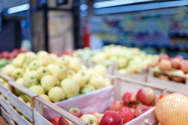 Soft focused shot of fruit department in grocery store, supermarket, mall, hypermarket or shopping center. Red, yellow and green apples in boxes. Healthy eating, avitaminosis  concept.  - Фото, изображение