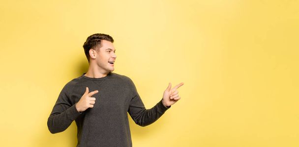 Young man pointing with fingers on yellow background, banner  - Фото, изображение
