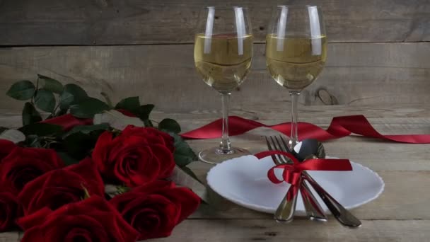 Κόκκινα τριαντάφυλλα κοντά. Δύο ποτήρια και μαχαιροπίρουνα. Δείπνο. Κόκκινη κορδέλα. Ευτυχισμένο Βαλεντίνο. Του Αγίου Βαλεντίνου. 4K - Πλάνα, βίντεο