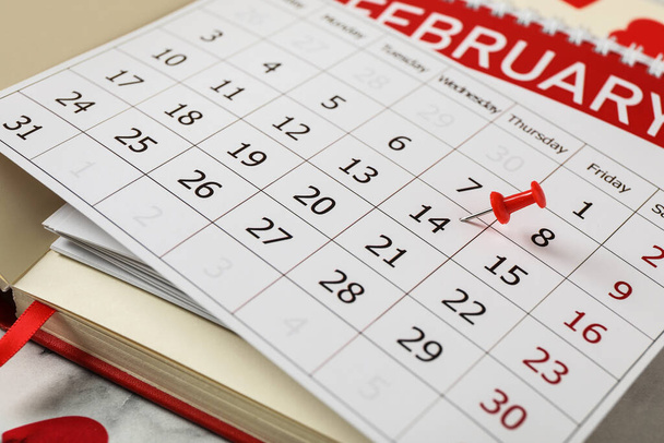 Kalendarz z zaznaczonymi Walentynkami i zeszytami na białym marmurowym stole, zbliżenie - Zdjęcie, obraz