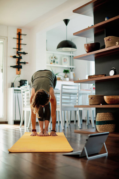 Woman practicing yoga at home with video tutorial. - Fotó, kép