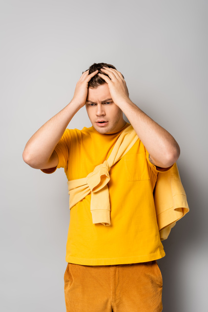 Worried man with hands near head looking away on grey background - Photo, image