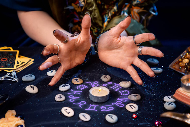Un adivino evoca una vela rodeada de runas y el resplandor de un círculo astrológico. El concepto de adivinación, astrología y predicción del futuro. - Foto, imagen