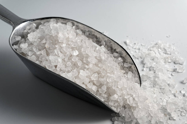 Θαλασσινό αλάτι σε μεταλλική σέσουλα σε λευκό φόντο - Φωτογραφία, εικόνα