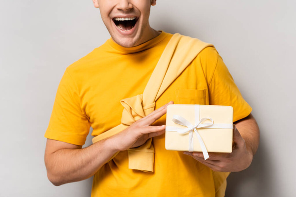 Cropped view of excited man holding present on grey background - Foto, Imagem