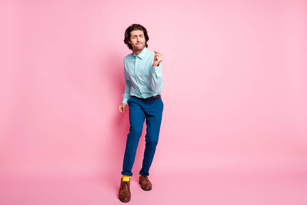 Full length photo portrait of carefree guy dancing snapping fingers isolated on pastel pink colored background with blank space - 写真・画像