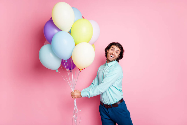 Photo portrait of glad guy holding air balloons with two hands isolated on pastel pink colored background - Fotoğraf, Görsel