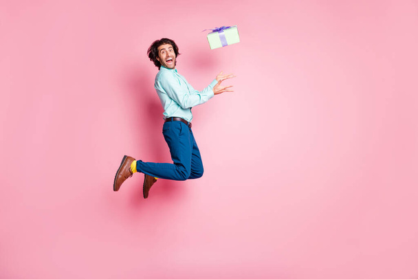 Full length photo portrait of guy catching gift box jumping up isolated on pastel pink colored background - Valokuva, kuva
