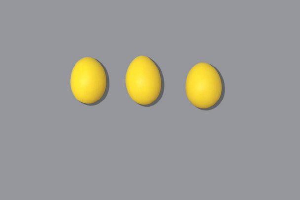 Huevos amarillos sobre un fondo gris. Color del año 2021. Huevos pintados para las vacaciones de primavera Pascua. composición minimalista en colores de moda. - Foto, Imagen