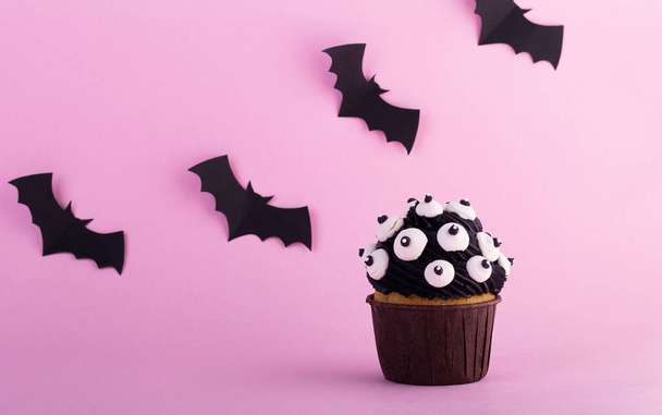 A mystical Halloween cupcake on a purple background. Cookies for Halloween. Composition for Halloween with sweets - Fotoğraf, Görsel