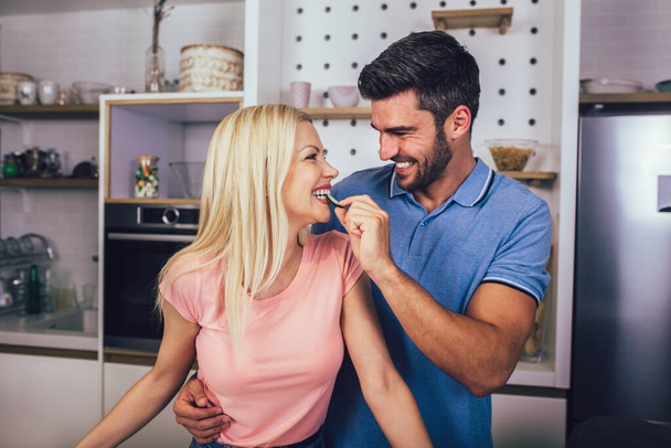 若いカップルは笑顔で家でキッチンで健康食品を調理しながら. - 写真・画像