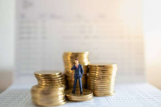 Obchodní, Money Investment and Planning Concept.Businessman miniaturní postava lidé postava stojící na hromadě zlatých mincí s bankovní vkladní knížkou. - Fotografie, Obrázek